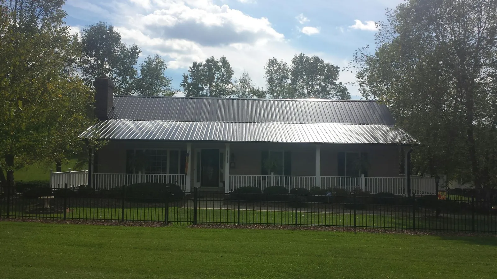 Gray metal roof on a brick ranch with a full width front porch — Gutter Guard Installation work by our crew in Caryville