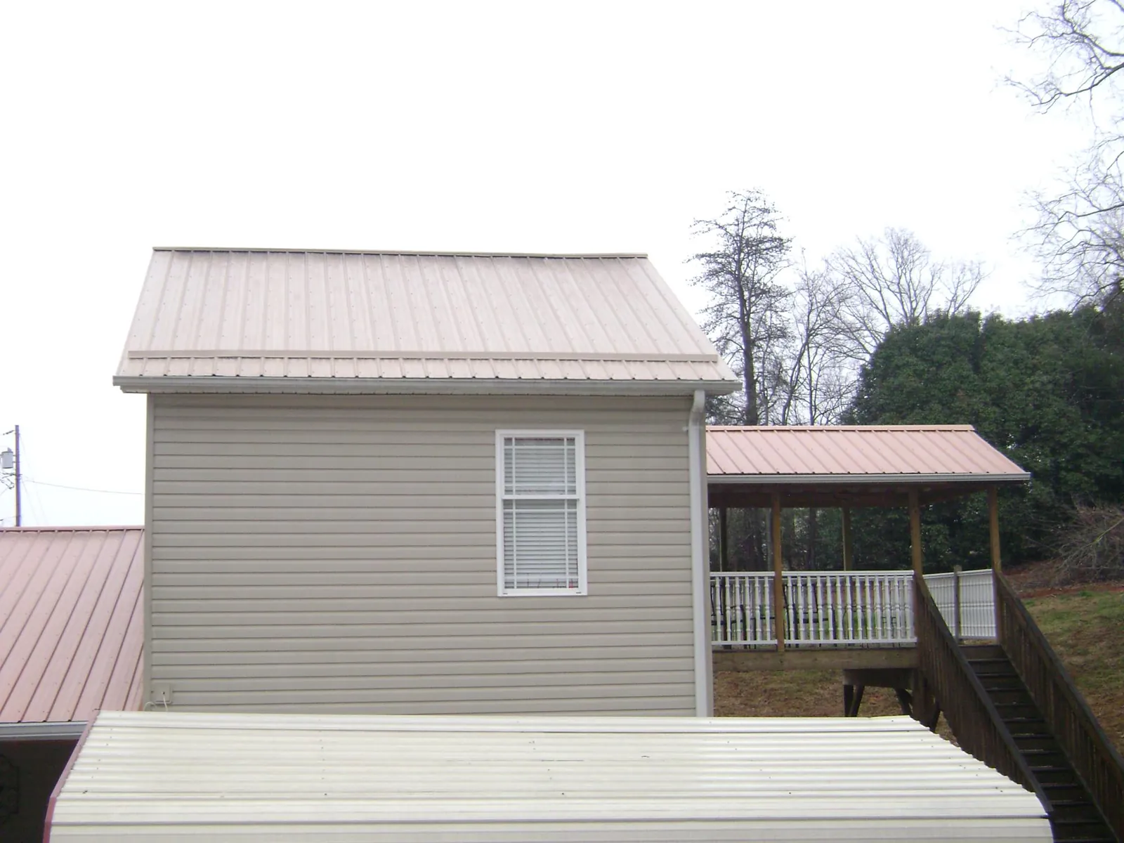 Tan metal roofs on a two story addition and attached porch, from a Roof Replacement job in Caryville