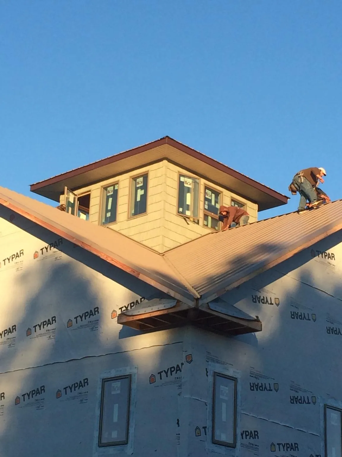 Roofers working around a rooftop cupola on a new metal roof at sunset — Roof Waterproofing in Caryville by Roofing Brothers